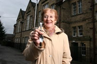 Colour photograph of the upper profile of Betty Tew holding a silver spoon.