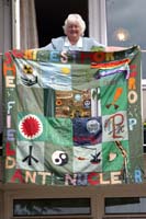 Colour photograph of Betty Smalley on her balcony holding a banner.