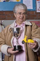 Colour photograph of the upper profile of Janet Boam holding a cup and plastic motorcycle.