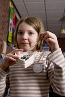 Colour photograph of the upper profile of Maddy Key holding a brooch.