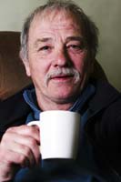 Colour photograph of the upper profile of John Lawson holding a mug of tea.