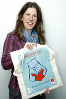 Colour photograph of the upper profile of Julia Shergold holding a Bookstart bag.