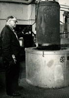 Black and white photograph of Tom Gould operating a furnace in the steel works. 1980s