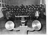 Black and white photograph of Errol Edwards holding cymbals in front of a band, 1976.