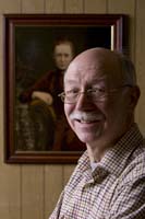 Colour photograph of Patrick Duggan next to a painting of his grandmother.