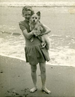 Sepia photograph of Marion Graham holding her dog on the beach, 1940s.