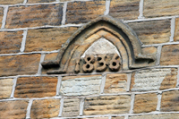 Colour photograph of the exterior front wall of Pitsmoor Village School showing the date the school opened carved in stone