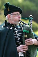 Colour photograph of an Irish piper playing in costume in Devon Gardens at a community event