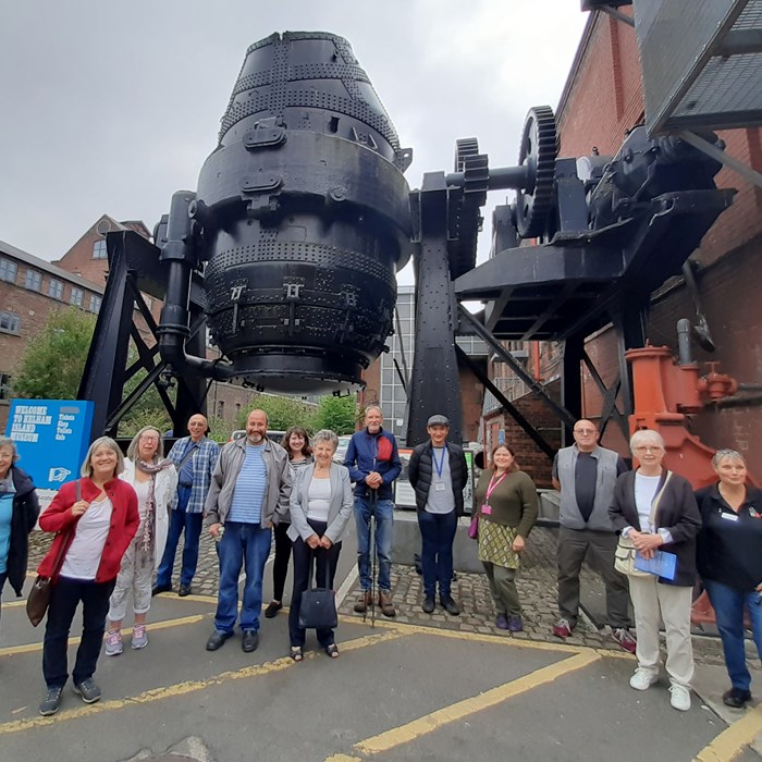 A group of adults standing in front of the Bessemer Converter 
