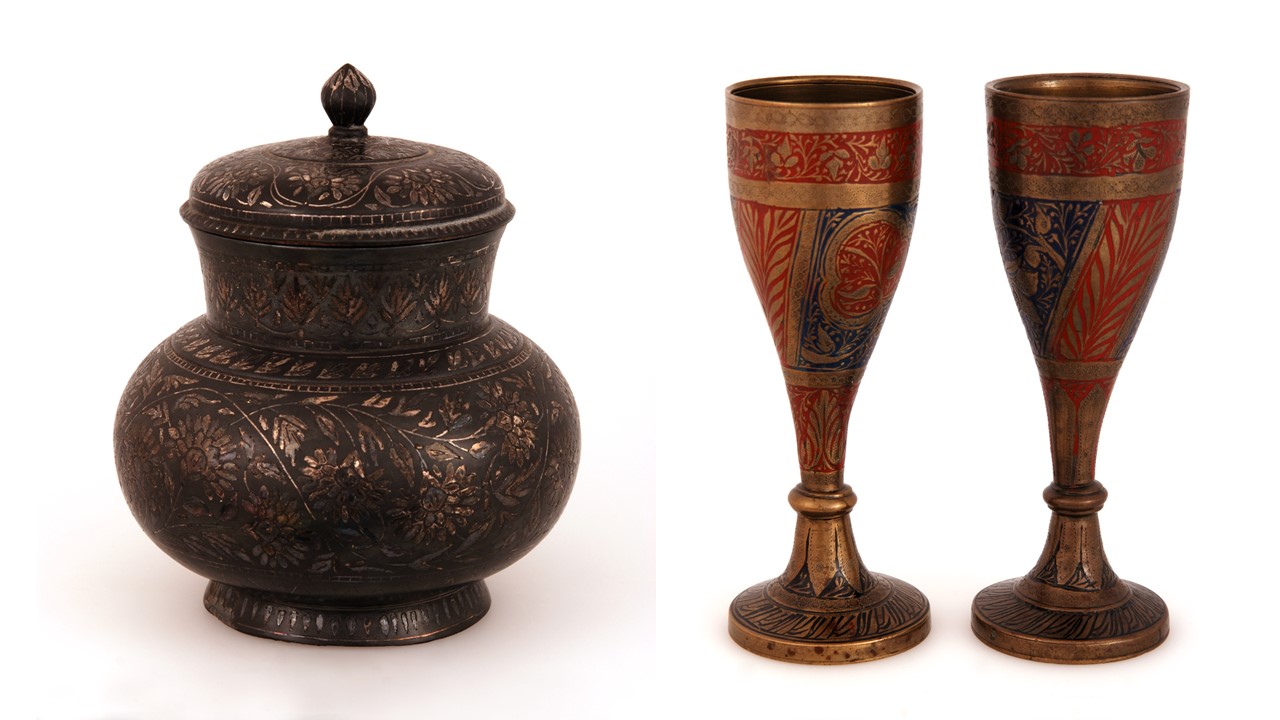 A photograph of two examples of South Asian metalwork against a white background. One is a brown/bronze lidded jar, the other is two golden drinking cups decorated with blue and red.