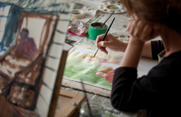 A close up of someone doing a watercolour painting for two figures.