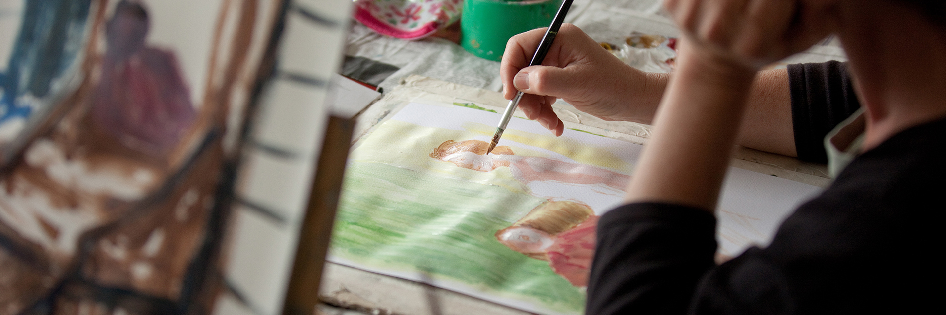 A close up of someone doing a watercolour painting for two figures.