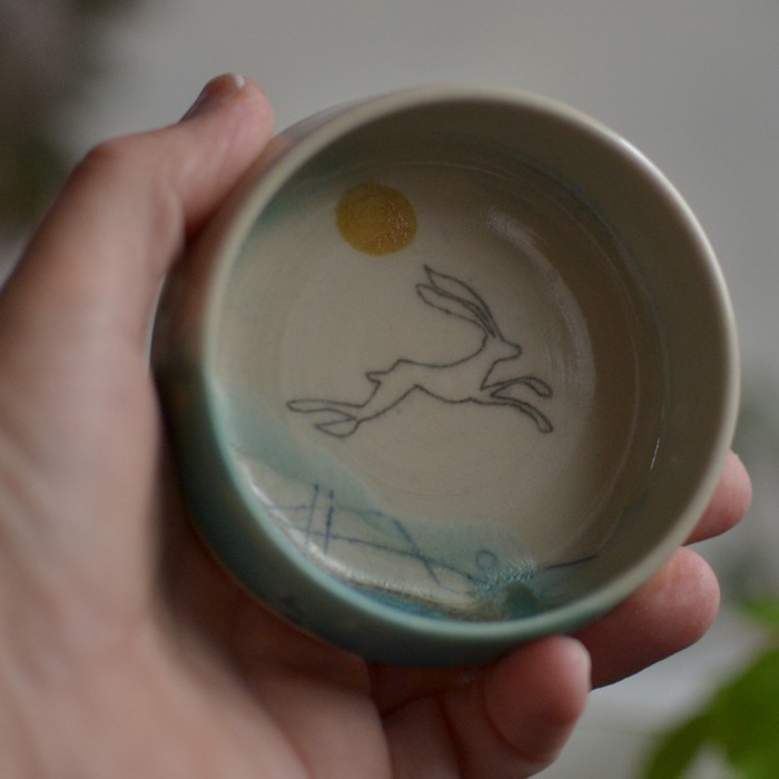 A small porcelain dipping bowl decorated with a drawing of a leaping rabbit.