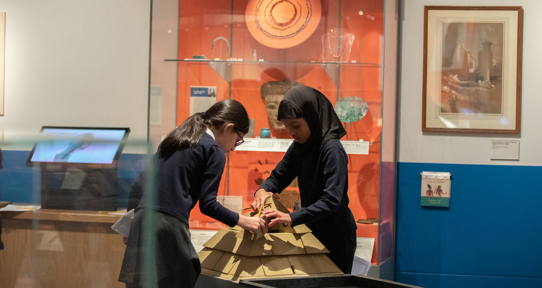 Two primary school students put together a wooden model of a pyramid, in the Ancient Egypt gallery.