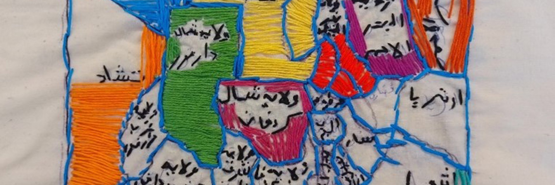 Embroidered outline of a house sectioned into brightly coloured shapes within and filled with words written in Arabic. 