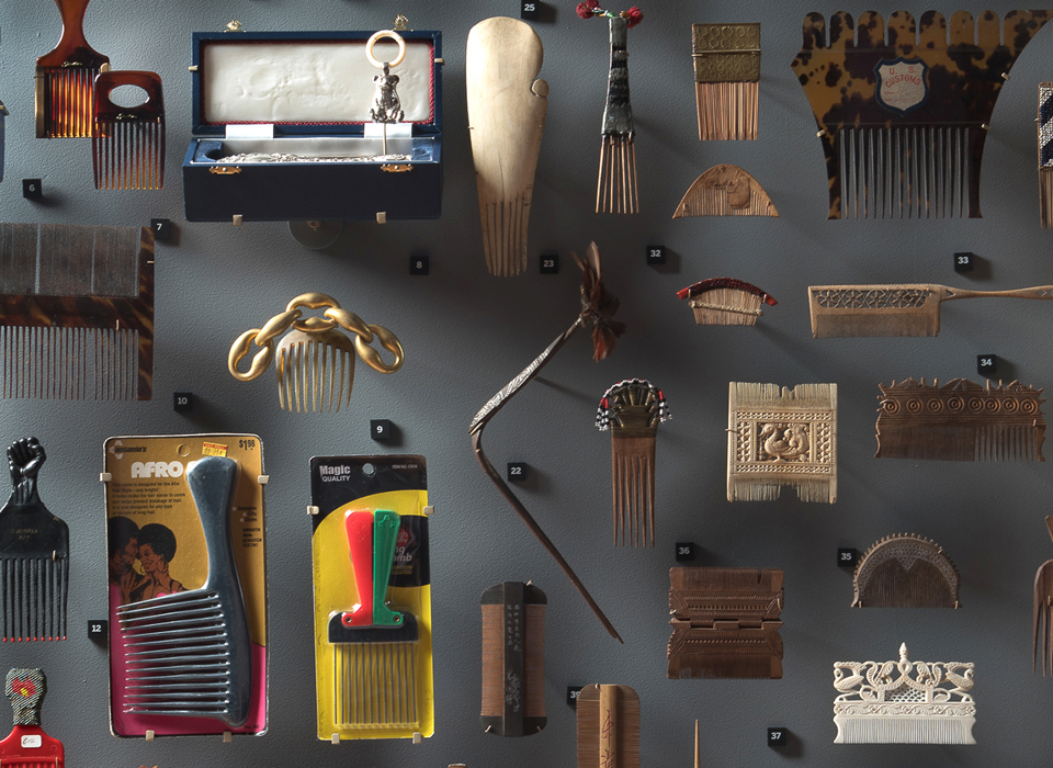 A photograph of numerous different styles of hair combs displayed on a wall. 