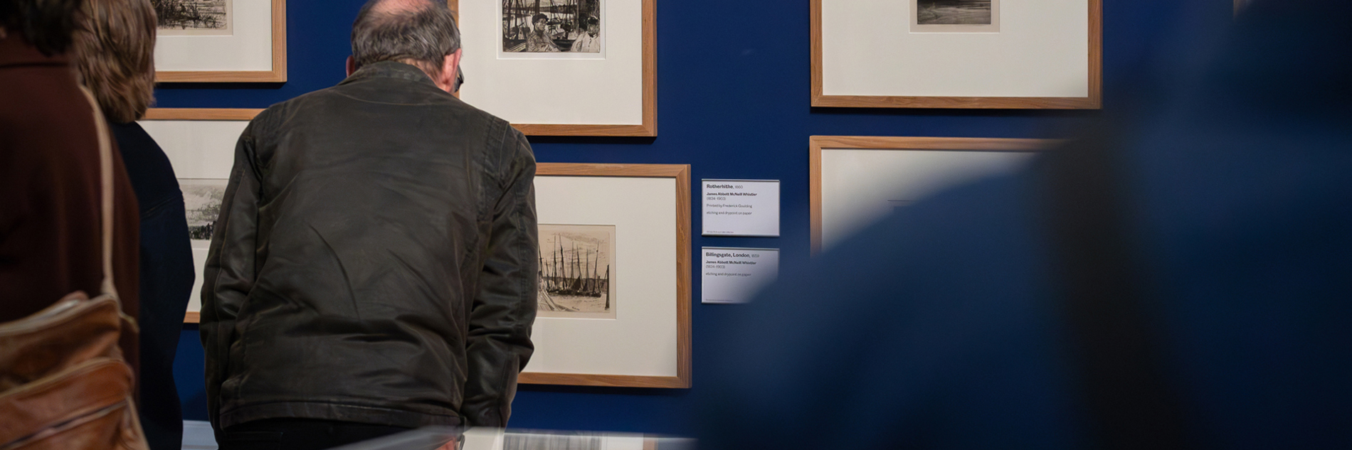 A photograph of adults looking at artworks in a gallery. 