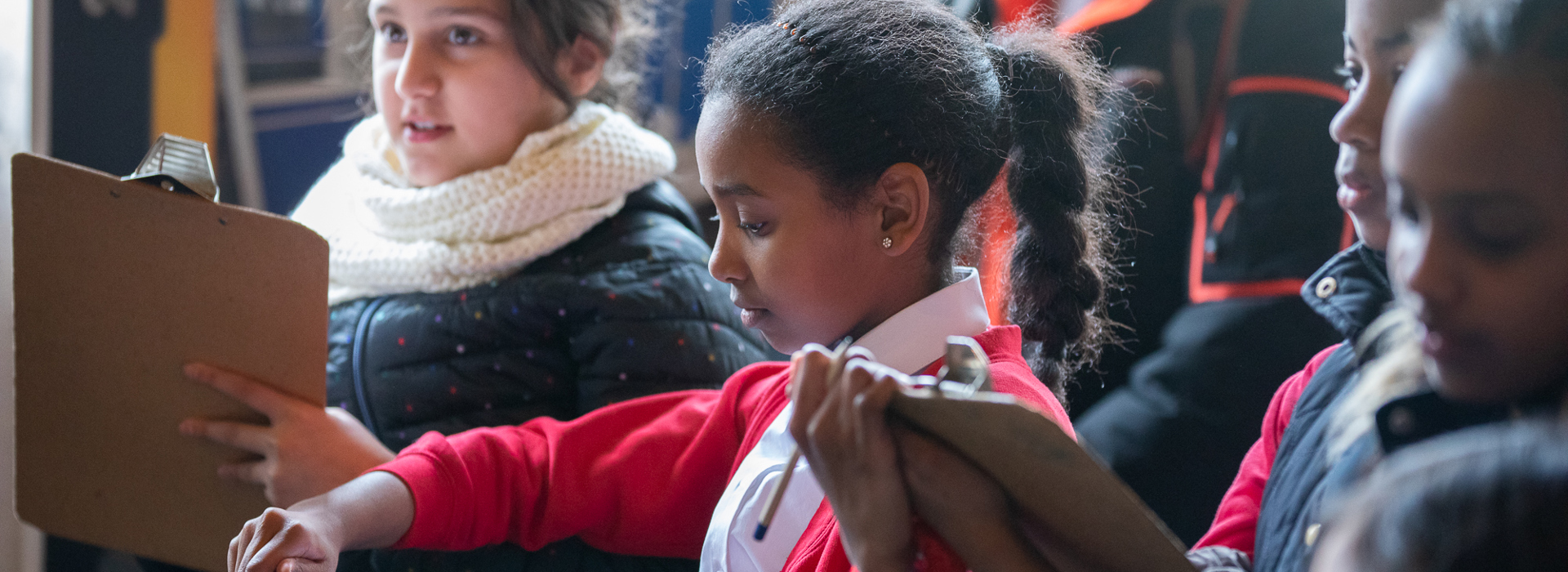 Five primary school aged children looking at clipboards.