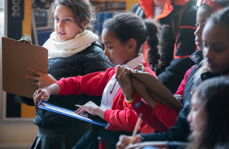 Five primary school aged children looking at clipboards.