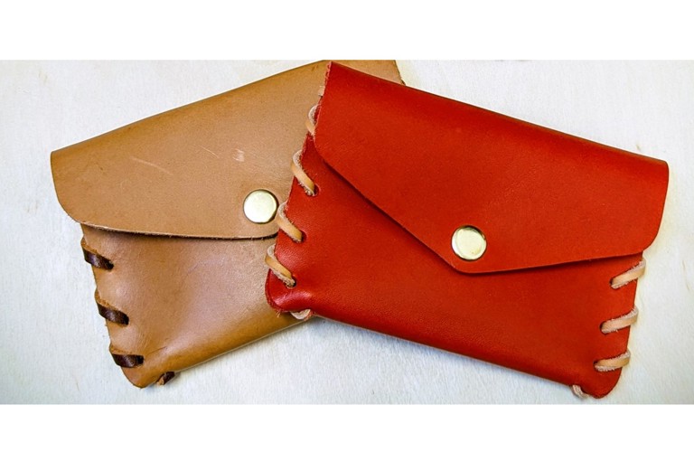 A photograph of two leather pouches, one is tan and the other is red. They are photographed against a white background.