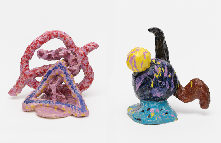 A composite image showing three works of ceramic sculpture by John Hoyland, all shown on a white background. 

The first sculpture (on the left of the image)  is Hoyland's work Thupelo Memory. A pink, yellow and blue painted triangle shape rests a top a pink, oval shaped base. A pink curved shape rests behind it, snaking up to the top of the triangle. Behind that is a large pink circle shape, with a line through it. All are decorated with splodges of red and burgundy paint.

The second is called The World. It is comprised of a black globe shape resting on a flared blue pedestal. A smaller yellow globe is attached to the upper left of the black globe, a black horn protrudes from the top, and a curved brown shape comes out of of the left side of the globe. Splashes of yellow, pink and black paint adorn the whole piece.

