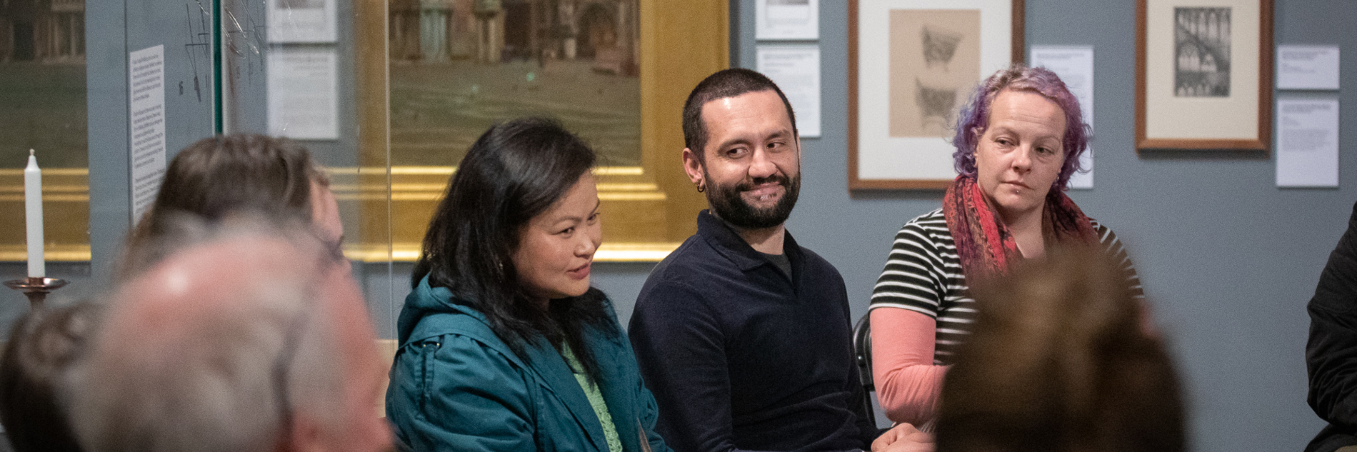 A photograph showing a group of adults sat in chairs in Graves Gallery, talking together. 