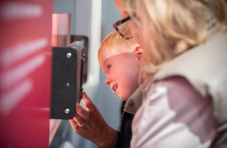 A child with an adult looking closely at a museum exhibit