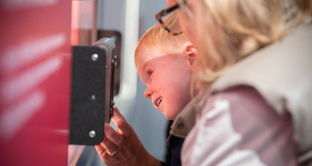 A child with an adult looking closely at a museum exhibit