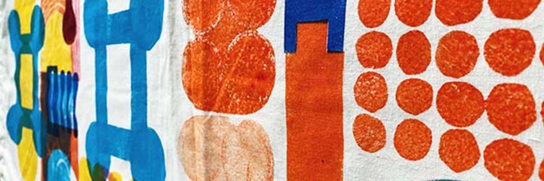 A photograph of material with orange, yellow and blue geometric shapes printed on it  