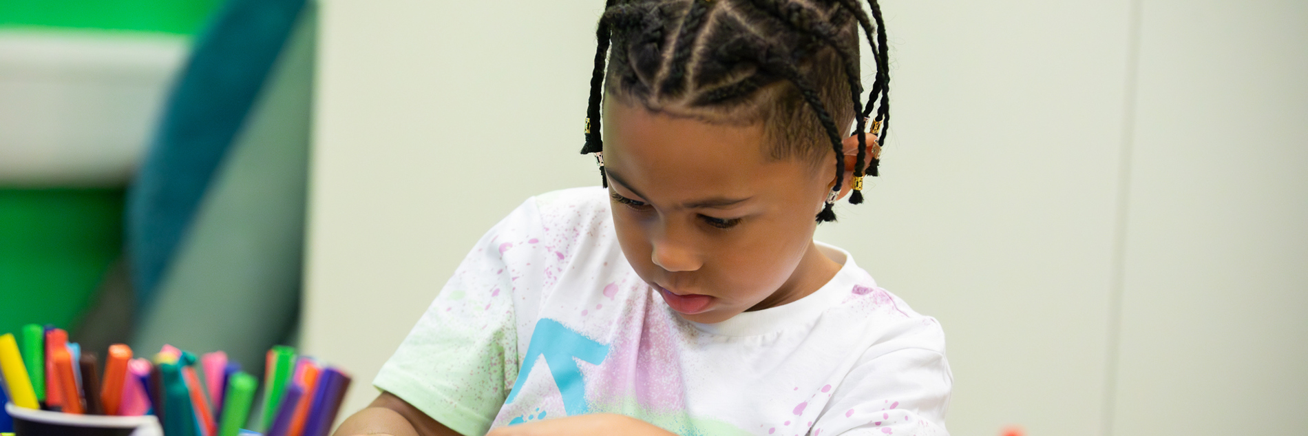 A child creating an artwork using coloured pens and sticking materials.