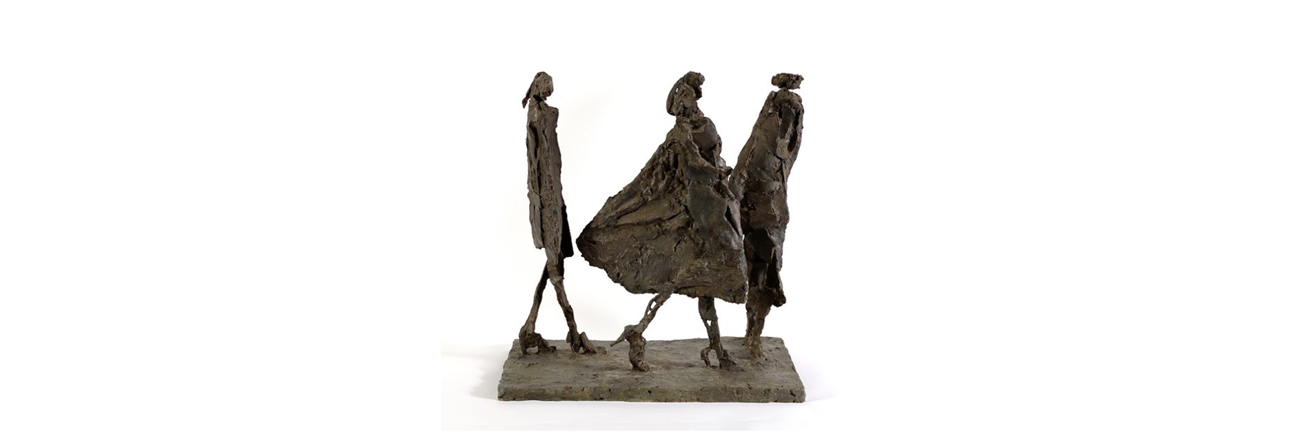 A photograph of a sculpture of three people caught in a walking motion. They are loosely sculpted in a brown medium.