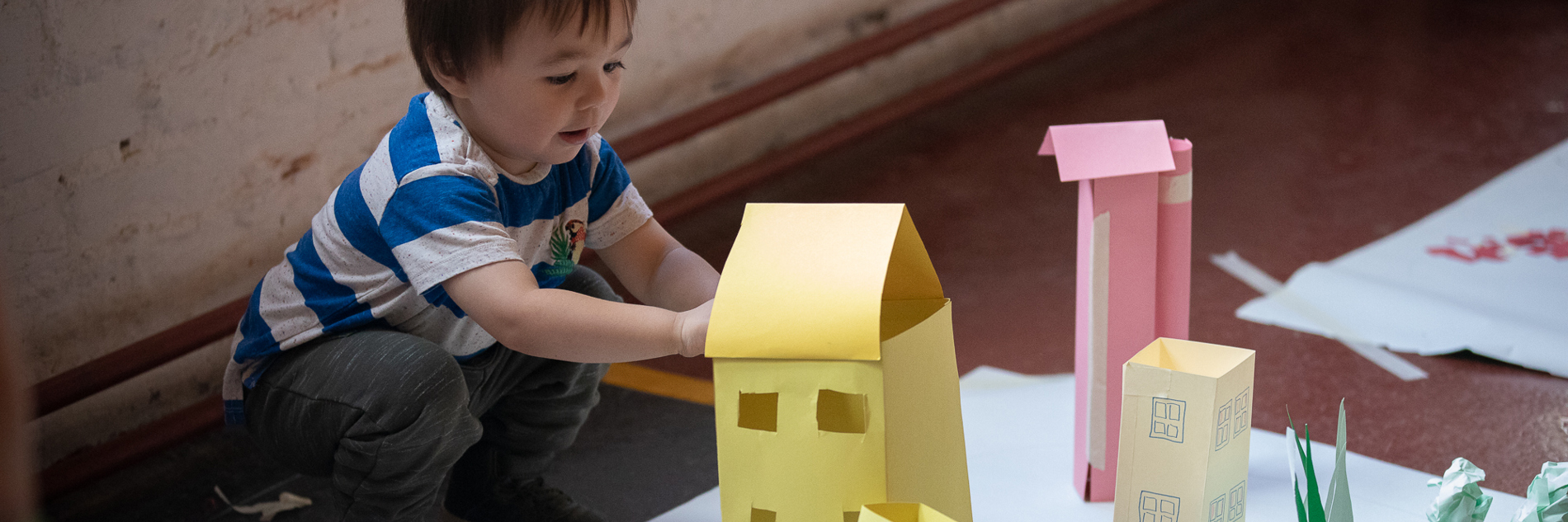 A photograph of a child making buildings from coloured paper. 