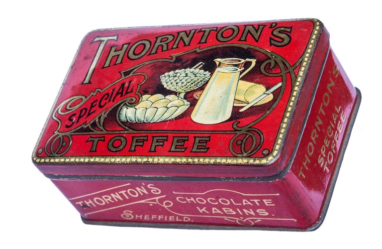 A red tin with the words Thornton's Special Toffee in gold. There is an illustration on the lid of a white jug of milk, a bowl of eggs and a plate of butter with a knife.