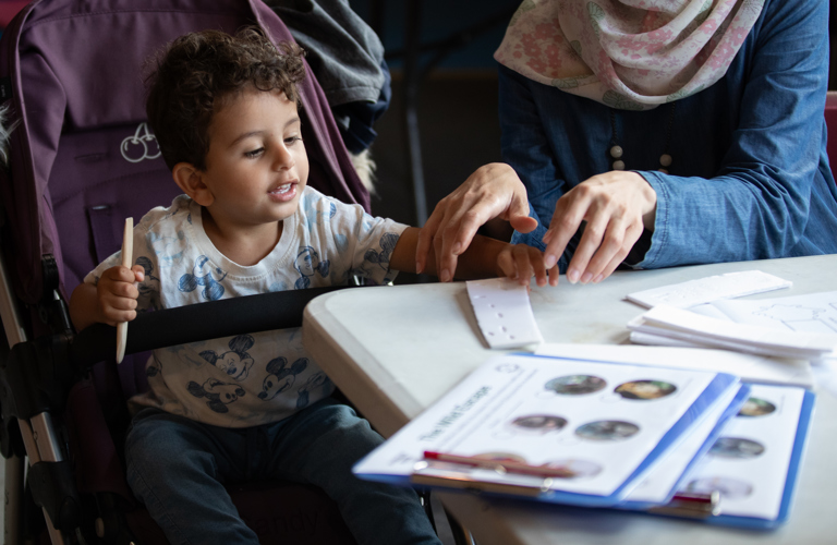 A photograph of a young boy and his mother preparing a polystyrene sheet for printing, using a wooden tool.