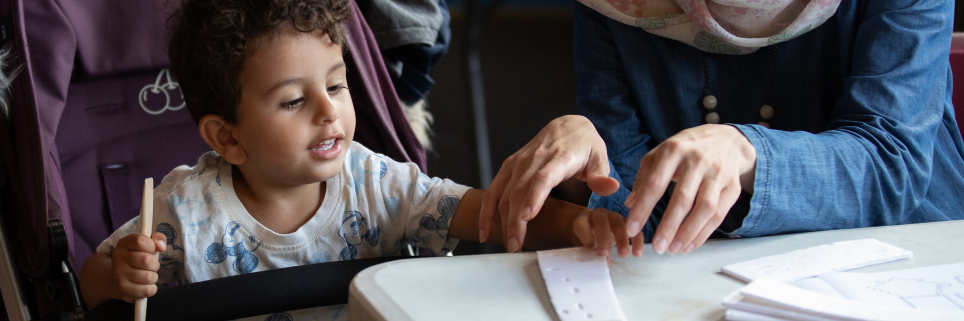 A photograph of a young boy and his mother preparing a polystyrene sheet for printing, using a wooden tool.