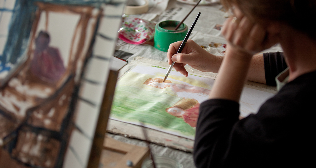 A close up of someone doing a watercolour painting for two figures.