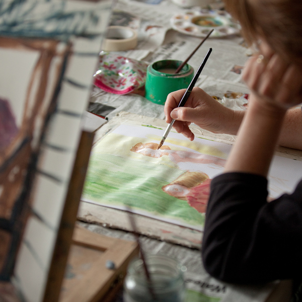 A close up of someone doing a watercolour painting for two figures.