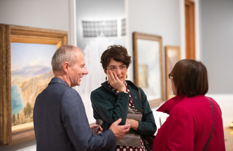 Three adults in conversation in an art gallery 