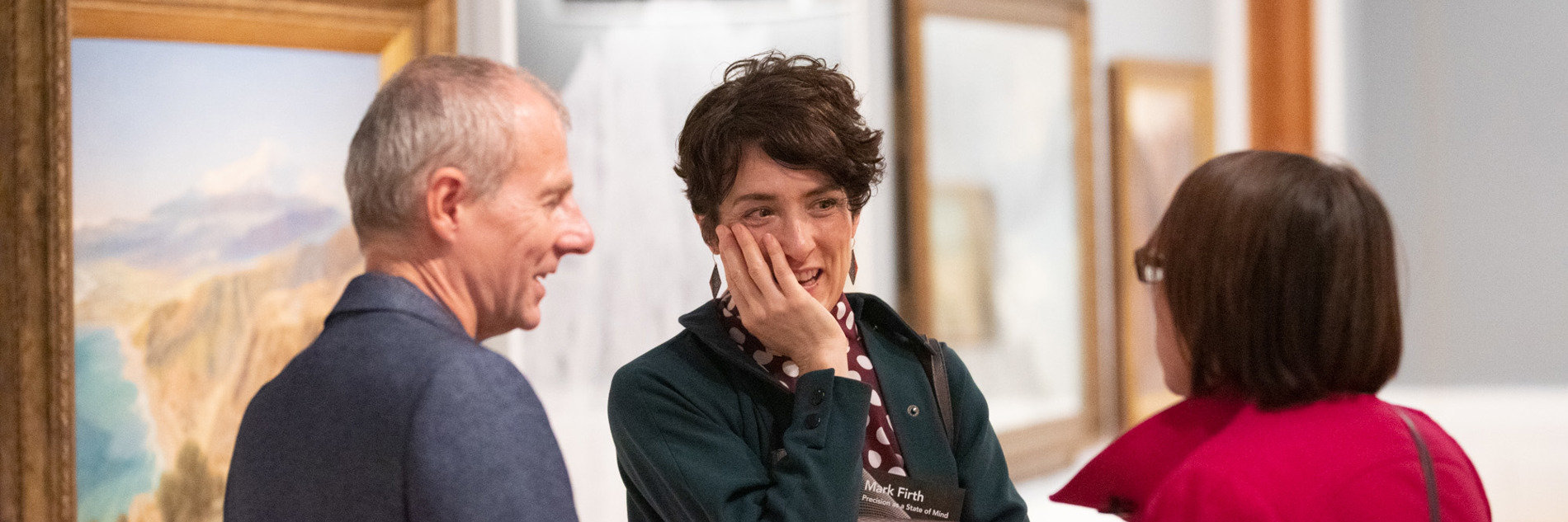 Three adults in conversation in an art gallery 