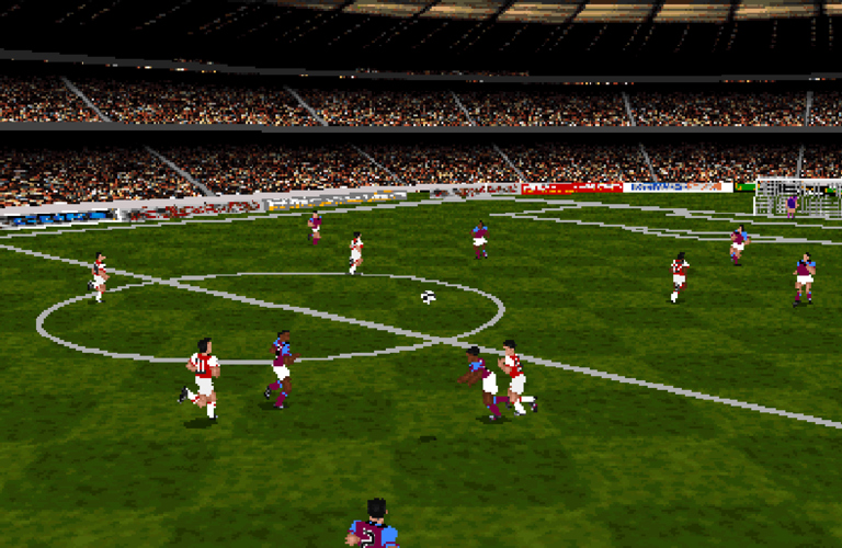 A screencap from the videogame Actua Soccer, showing multiple football players on a football pitch. It is a game from the 90s, so quite pixelated.