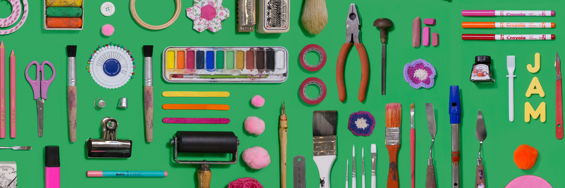 A selection of different crafting utensils (ink rollers, pliers, paint brushes etc) arranged on a green background.