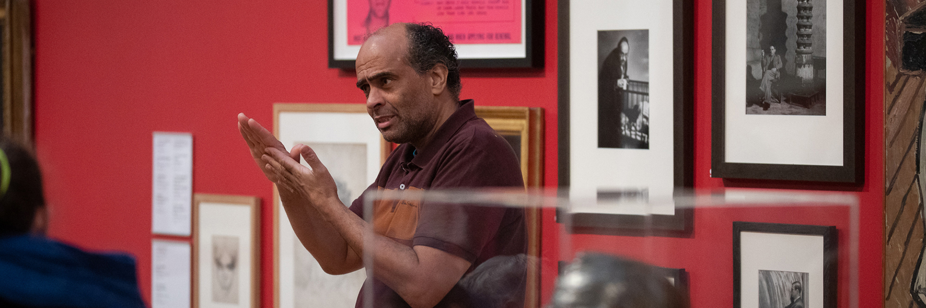 An adult giving a tour of an art gallery, using British Sign Language.