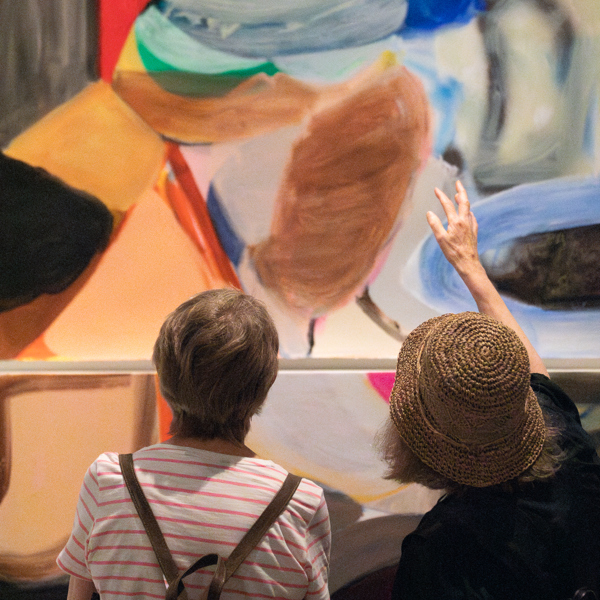 Two visitors look at a large and colourful abtract painting