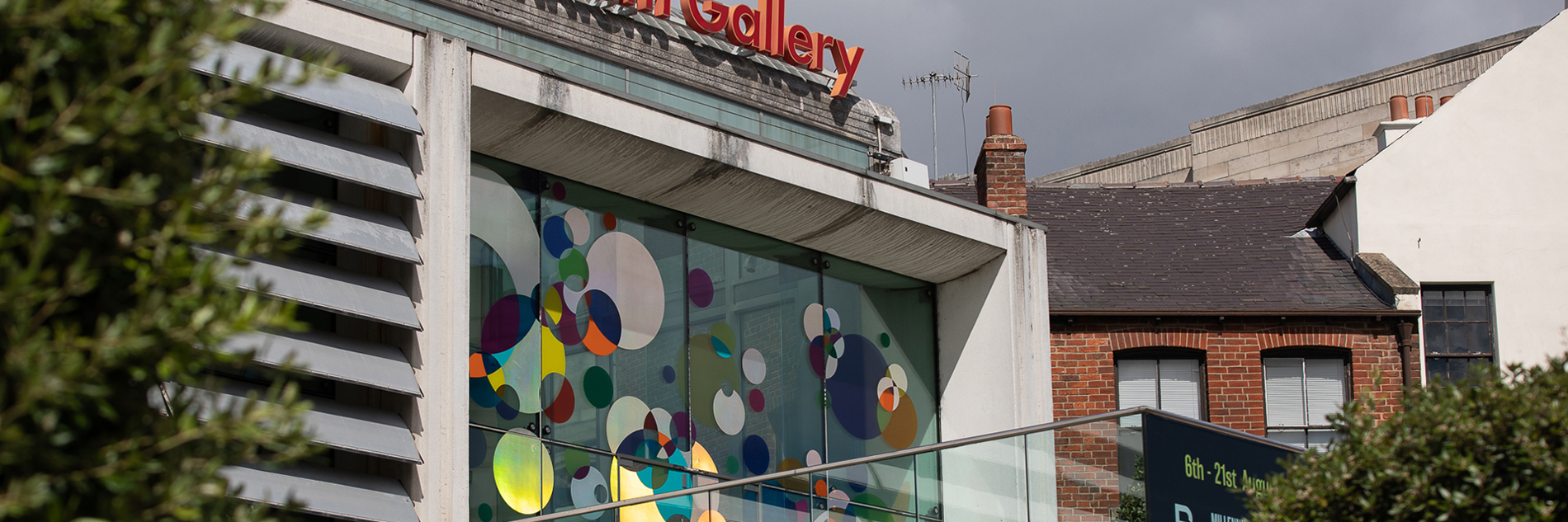 The external, upper glass door and windows of the Millennium Gallery which has multiple, multicoloured shaped dots in red, blue, yellow, green and blue on them