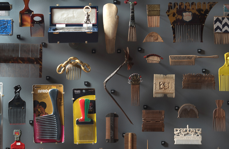 A photograph of numerous different styles of hair combs displayed on a wall. 