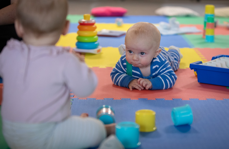 Babies playing with stacking toys.