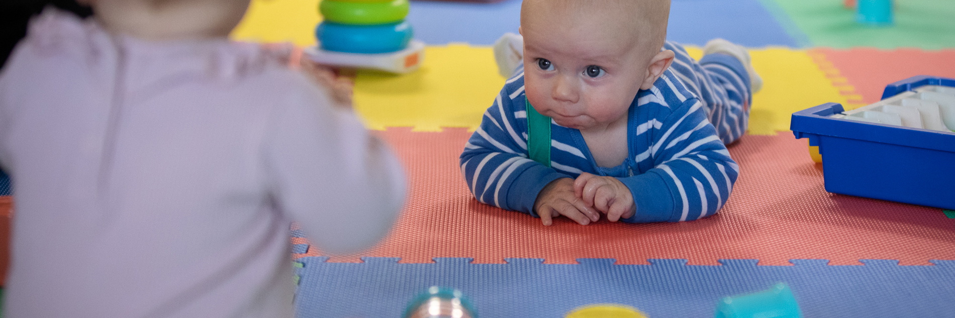 Babies playing with stacking toys.