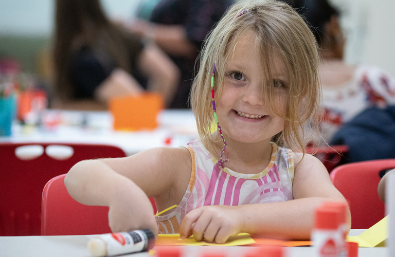 A child sitting at a table doing a craft activity. 