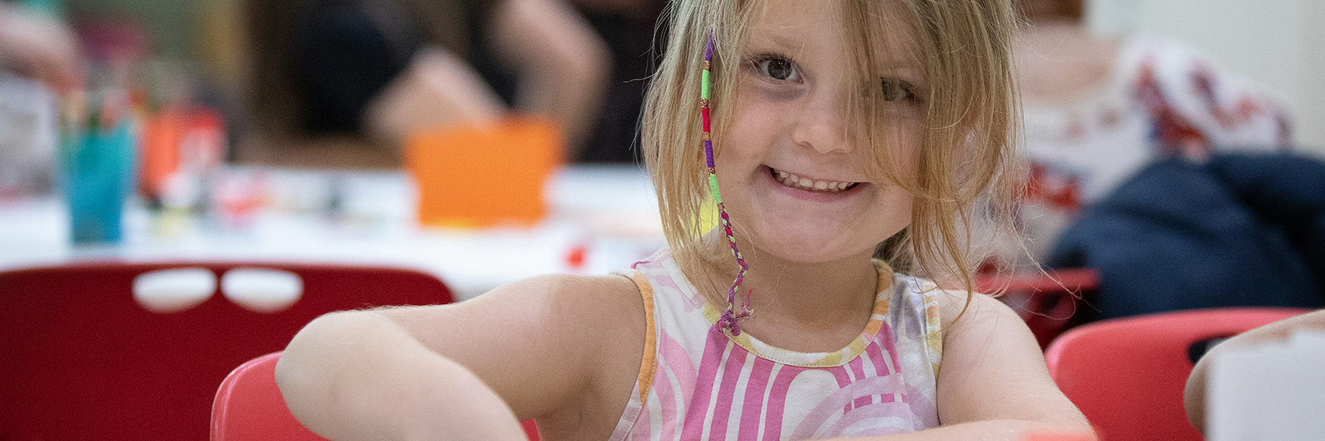 A child sitting at a table doing a craft activity. 