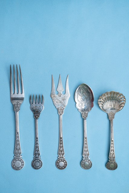 Decorative forks and spoons laid flat against a pale blue background.